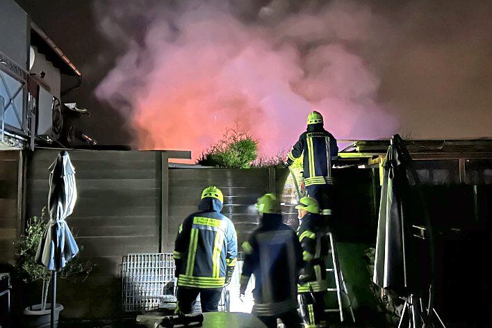 Auch den Weg über ein Nachbargrundstück wählt die Feuerwehr, um den Brand der Gartenhütte zu löschen. Fotos: Klaus-Dieter Häring