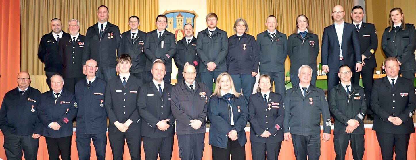 Kreisbrandinspektor Frederik Stahl (hinten, Zweiter von rechts) und Kreisbrandmeister René Schultheis (hinten, links) können vielen Aktiven der Feuerwehren des Marktfleckens Ehrungen des Verbands überreichen. Fotos: Dorothee Henche